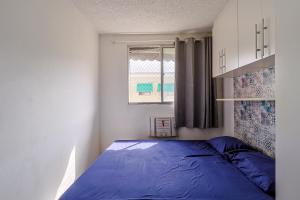 a bedroom with a blue bed and a window at Apto com ar-condicionado e vaga em Honorio Gurgel in Rio de Janeiro