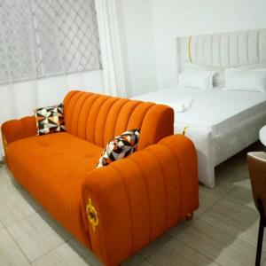 an orange couch and a bed in a room at Chasy luxury in Mtwapa