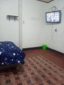 a room with a bed and a tv on a wall at Habitación Plaza Chosica in Chosica
