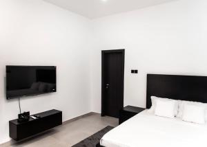 a bedroom with a bed and a flat screen tv at The Kottage Studio Apartment A in Accra
