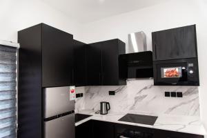 a kitchen with black cabinets and a white counter top at The Kottage Studio Apartment A in Accra +5 photos