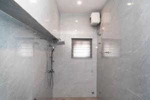 a bathroom with a shower stall and a window at The Kottage Studio Apartment A in Accra