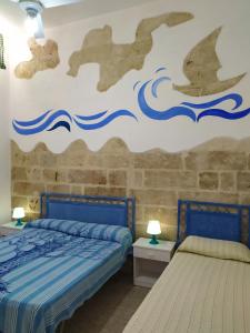 a bedroom with two beds and a wall with waves at Villetta vista mare Donna Lisa in Capilungo