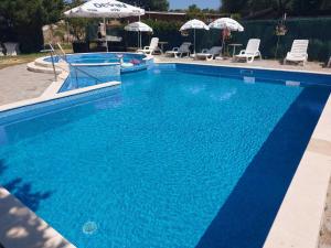 a large blue swimming pool with chairs and umbrellas at Lozenets Oasis Beach Home Lila in Lozenets +5 photos