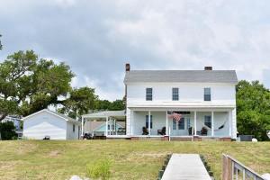 una casa bianca con un molo di fronte di Comfortable Down East Waterfront Farmhouse a Sealevel
