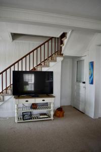 un soggiorno con TV a schermo piatto e scala di Comfortable Down East Waterfront Farmhouse a Sealevel Altre 46 foto
