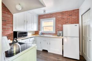una cucina con mobili bianchi e un muro di mattoni di Cozy Boho 1BR - Walk to Shops & Cafes a Portland