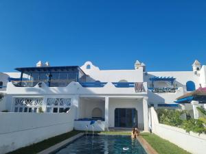 a man standing in a swimming pool in front of a house at Private villa with pool in Bouznika