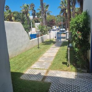 a walkway with grass and palm trees on a street at Private villa with pool in Bouznika +14 photos