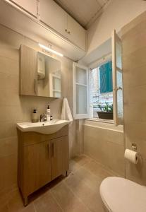 Un baño con lavabo, inodoro y ventana. en The Tailor's House, en Corfu