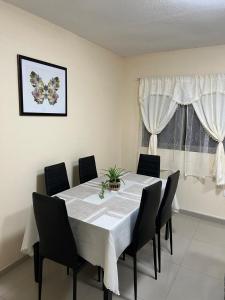 a dining room with a white table and black chairs at Apartamento lindo centro económico Antofagasta in Antofagasta