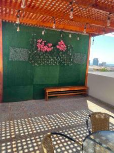 a patio with a table and pink flowers on a green wall at Apartamento lindo centro económico Antofagasta in Antofagasta +3 photos
