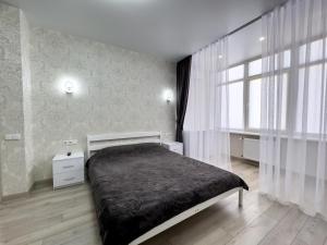Un dormitorio con una cama y una ventana grande. en Апартаменты Kadorr 54, en Odessa