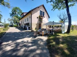 a building with people sitting on benches in front of it at Lovačka kuća Draganić in Draganići