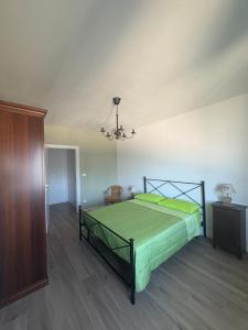 a bedroom with a green bed and a chandelier at Tramonto sul Viso in Saluzzo