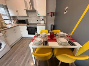 リバプールにあるAnfield Courtyard Retreatのキッチン(ダイニングテーブル、黄色い椅子付)