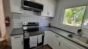 eine Küche mit einem Herd, einem Waschbecken und einem Fenster in der Unterkunft 4-Bedroom Home by Downtown and Airport in Calgary + 37 Fotos