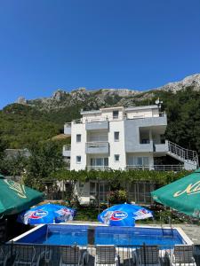 a hotel with two umbrellas in front of a building at Apartmani Planinska Idila in Bar