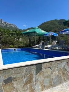 a swimming pool with chairs and umbrellas at Apartmani Planinska Idila in Bar