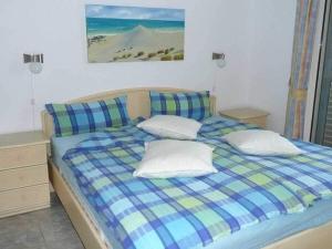 een bed met een blauwe geruite deken en kussens bij Bungalow with 2 bedrooms in Costa Calma