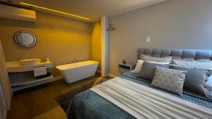 a bedroom with a bed and a tub and a sink at Loft novíssimo com banheira imersão aquecida a 5min da Vila Germânica in Blumenau