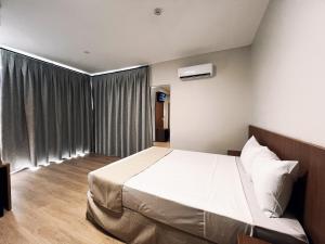 a bedroom with a large bed with white sheets at Rota Hotéis Rio Verde in Rio Verde +56 photos