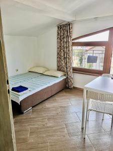 Un dormitorio con una cama y una mesa y una ventana. en Paunovi Guest House, en Primorsko