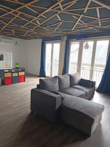 a living room with a couch in a room with windows at Grand appartement avec belle vue in Uzerche