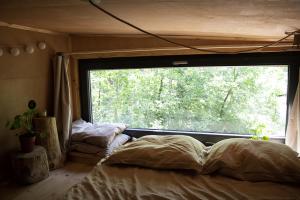 una cama en una habitación con una ventana grande en Carthome - wyjątkowe miejsce leśnego wypoczynku, en Zynie