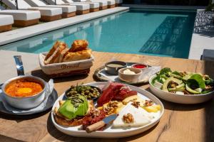 a table topped with plates of food next to a pool at Wakana Alaçatı in Alaçatı