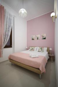 a white bedroom with a large bed with pink sheets at CGarden in Reggio Calabria +29 photos