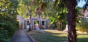 een terras met een tafel en stoelen in een tuin bij Les bananiers in Bergerac