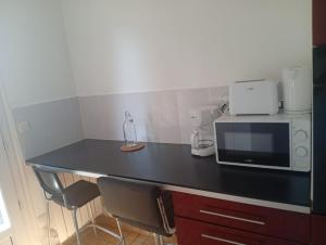 a kitchen with a black counter top with a microwave at Maison 2 - entre ville et verdure in Saint-Pryvé-Saint-Mesmin