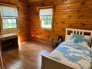 Dormitorio con cama y escritorio en una cabaña de madera en Log Cabin with Tiny Farm, en Dunnville