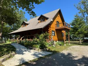 una casa de troncos con porche y balcón en Log Cabin with Tiny Farm, en Dunnville