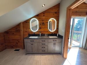 un baño con lavabo y dos espejos en Log Cabin with Tiny Farm, en Dunnville 61 fotos más