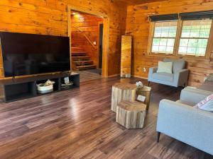 Cabaña de madera con sala de estar con TV de pantalla plana grande. en Log Cabin with Tiny Farm, en Dunnville