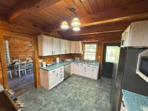 Una cocina con gabinetes blancos y un refrigerador negro. en Log Cabin with Tiny Farm, en Dunnville