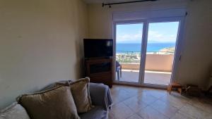 a living room with a couch and a sliding glass door at Alexandras Villa in Skala Marion