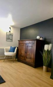 a living room with a wooden cabinet and a chair at Maison de ville Le troubadour in Sarlat-la-Canéda