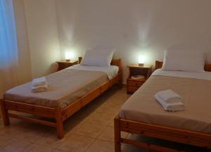 two beds in a room with two lamps on tables at Epiphany Moudros Apartment in Moúdhros