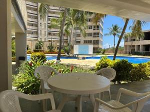 a white table and chairs on a patio with a pool at Ocean Blue Isla de Margarita in Porlamar