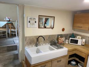 eine Küche mit einem weißen Waschbecken und einer Mikrowelle in der Unterkunft La Petite Maison, Perrou, Normandy, Orne in Perrou + 55 Fotos