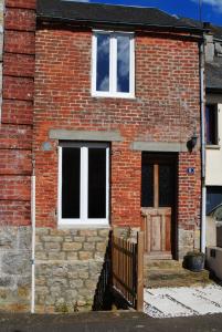 ein Backsteinhaus mit zwei Fenstern und einer Tür in der Unterkunft La Petite Maison, Perrou, Normandy, Orne in Perrou