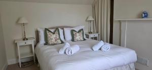 a white bed with pillows on it with two tables at Yeomans Cottage in Pitlochry