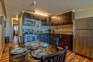 Una cocina con una mesa con sillas y un refrigerador. en Modern Ground Floor Beachfront Condo Suite - Sleeps 4 - Pool and Sauna, en Lincoln City