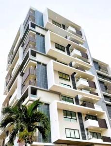 a tall building with a palm tree in front of it at Stellar City Apartment at Solaris in Accra