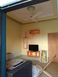a living room with a ceiling fan and a tv at Hollande House Blm in Ouagadougou