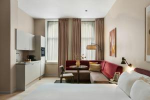 a living room with a red couch and a kitchen at VCity Suites at The Teacher in Glasgow