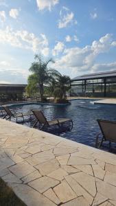 ein Swimmingpool mit zwei Liegen am Wasser in der Unterkunft Bangalô Kyalami Wake Park in Várzea Grande